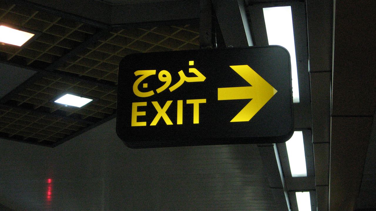 An illuminated exit sign in Persian and English